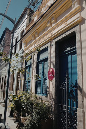 The image depicts a charming facade of a historic building with blue-painted windows and wooden...