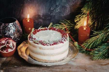 A beautifully decorated layered cake with white frosting, topped with fresh berries and greenery,...