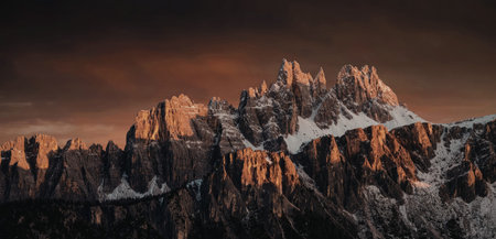 A breathtaking view of a snow-capped mountain range illuminated by the warm hues of a setting sun....
