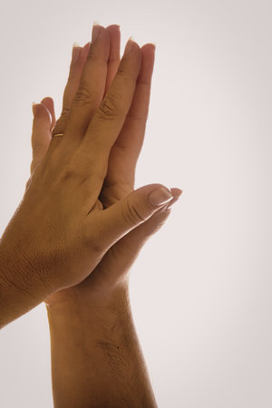 An image of two hands clapping together, with sunlight casting a warm glow on them. The hands are...