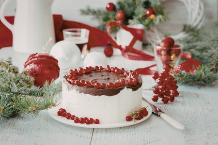 A beautifully decorated cake with white frosting and red berries sits on a wooden table surrounded...