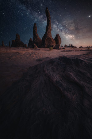 A captivating nighttime scene featuring tall rock formations silhouetted against a starry sky with...