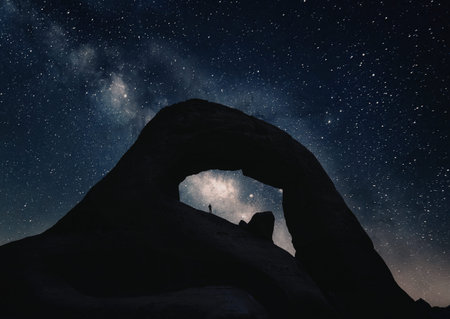 A stunning night sky filled with stars and the Milky Way galaxy is visible through an arch in a...