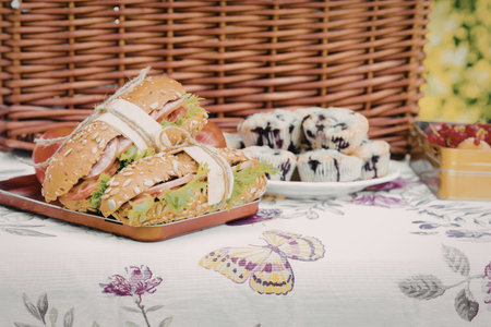 A delightful picnic setup featuring a sandwich, cookies, and a basket, all arranged on a...