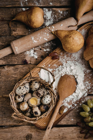 A rustic wooden table set with baking ingredients including pears, eggs, flour, and baking tools....
