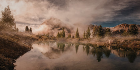 A tranquil mountain lake reflects the sunrise, surrounded by misty forests and rugged peaks.
