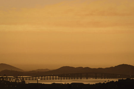 A serene sunset over a mountain range with a body of water reflecting the warm hues of the sky.の写真素材