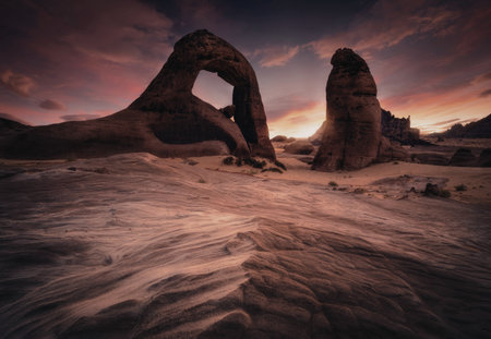A stunning sunset illuminates unique rock formations, casting warm hues across the sky and sand.の写真素材