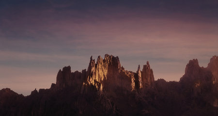 A captivating image of a rugged mountain range bathed in the warm, golden hues of sunset. The sky...