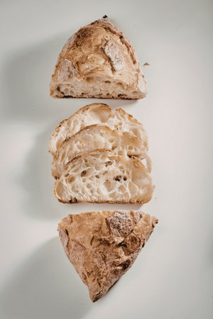 A close-up image of three slices of artisanal bread, showcasing their crusty exterior and soft, airy interior. The bread slices are arranged vertically on a plain background.の写真素材