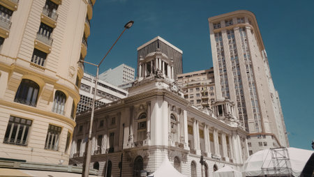 A vibrant cityscape featuring a historical building with classical architecture surrounded by modern high-rise buildings under a clear blue sky.の写真素材