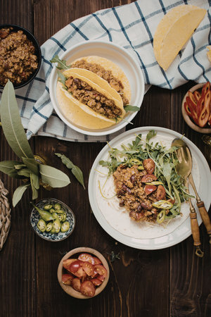 A delightful arrangement of Mexican cuisine featuring tacos and a fresh salad on a rustic wooden table. The image includes tortillas, sliced vegetables, and garnishes.の写真素材