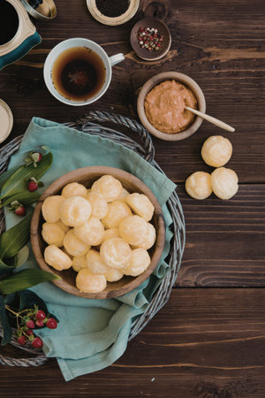 A rustic wooden table set with a basket of snacks, a cup of tea, and various condiments. The table...