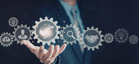 A businessman in a blue suit is holding a series of digital gears and icons representing various business concepts. The image emphasizes technology, innovation, and business strategy.の写真素材