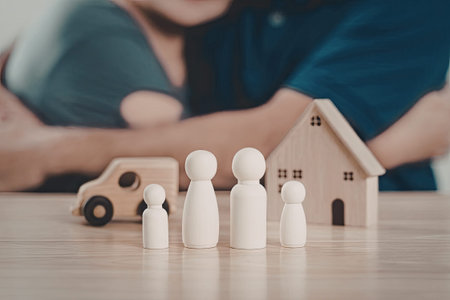 A family is engaged in a playful activity with wooden toys, including a house and a car, on a wooden...