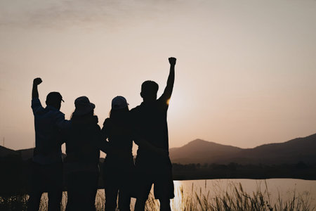 A group of friends standing together, raising their fists in celebration against a backdrop of a...