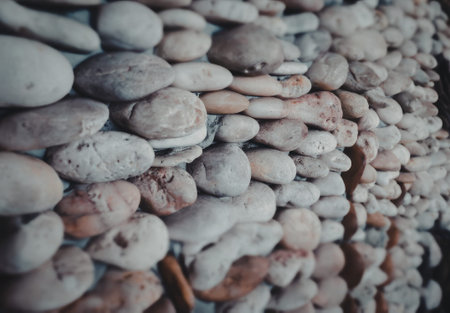 A close-up view of a variety of smooth stones stacked together, showcasing different shades of gray,...