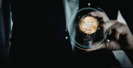 A close-up image of a hand holding a digital lightbulb that emits a glowing idea, symbolizing...