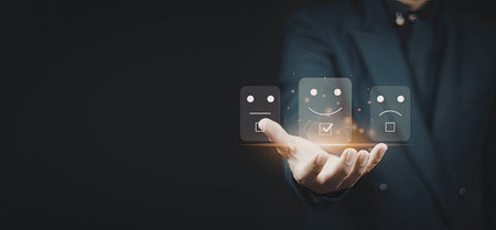 A hand is shown interacting with a set of digital icons representing different emotional states, including happy, neutral, and sad faces. The background is dark, emphasizing the glowing icons and the hand.の写真素材