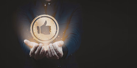 An image featuring a pair of hands holding a glowing golden like symbol, representing approval, positivity, or success.の写真素材