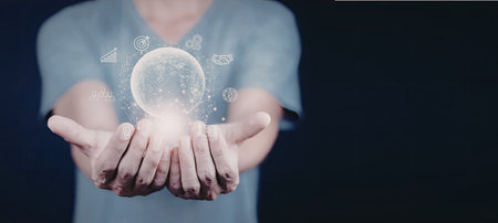 A person is holding a glowing digital globe in their hands, surrounded by floating icons representing various digital elements.の写真素材
