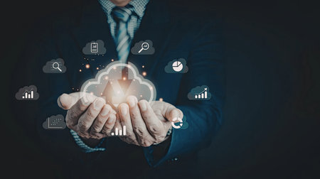 A close-up image of a person's hands holding a glowing cloud with various technology icons surrounding it, symbolizing digital innovation and cloud computing.の写真素材