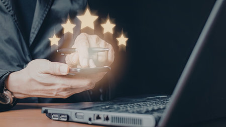An image of a person holding a smartphone with a starry design above it, next to a laptop computer....