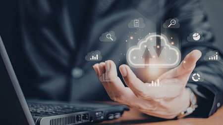 A close-up image of a person's hands interacting with digital cloud and data icons above a laptop....