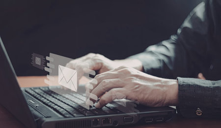 An image of a person's hands typing on a laptop keyboard with floating email icons above the keys.