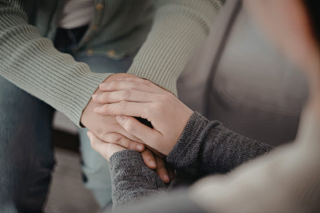 An image capturing a close-up of two hands gently holding each other, conveying a sense of support...