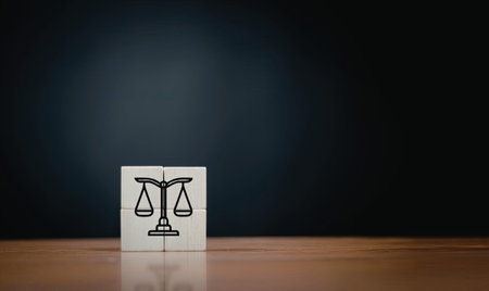 A wooden block with a justice symbol, consisting of a pair of scales, placed on a reflective surface...