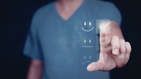 A person wearing a blue shirt interacts with a digital interface displaying a smiley face, likely...