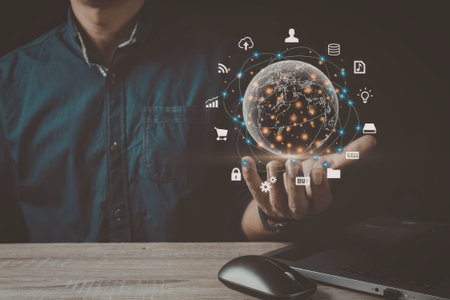 A man in a blue shirt is interacting with a digital globe surrounded by various technological icons,...