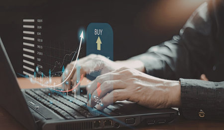 A close-up image of a person's hands on a laptop keyboard, with virtual elements indicating stock...
