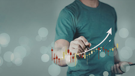 A man in a blue shirt is interacting with a financial graph, indicating an upward trend. The image...