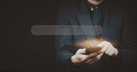 A close-up image of a person holding a smartphone, interacting with a futuristic search interface projected from the device.の写真素材