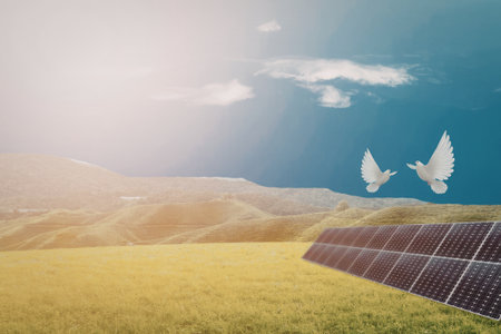 A serene landscape featuring solar panels in a green field under a clear blue sky with two white doves flying above.の写真素材