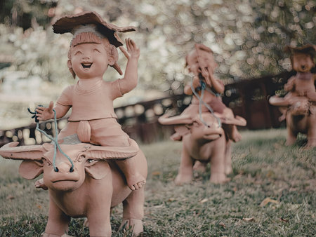 A group of playful terracotta figurines is displayed in a verdant garden setting. Each figurine is...