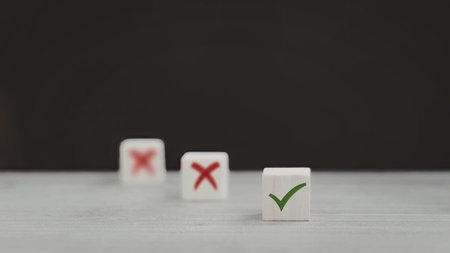 An image of three dice placed in a row on a flat surface. Two dice display red crosses, while the third die shows a green checkmark.の写真素材