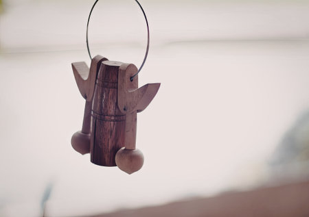 A wooden angel ornament with delicate wings and a simple, rustic design hangs gracefully, capturing a moment of tranquility.の写真素材