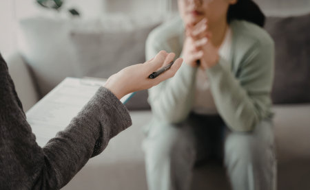 An image depicting a person holding a small object while conversing with another individual in a living room setting.の写真素材