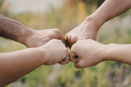 An image of multiple hands coming together to form a fist bump, symbolizing unity and teamwork. The...