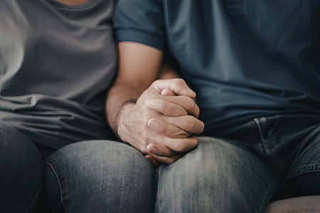 Close-up image of a person's hands resting on their lap. The person is wearing a blue shirt and jeans.の写真素材