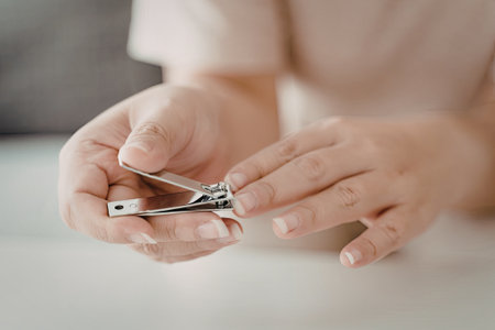 A close-up image of a person's hands using nail clippers to trim their fingernails.の写真素材
