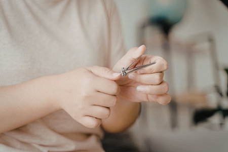 A close-up image of a person holding a pair of nail clippers, showcasing the tool's details and the person's hand.の写真素材
