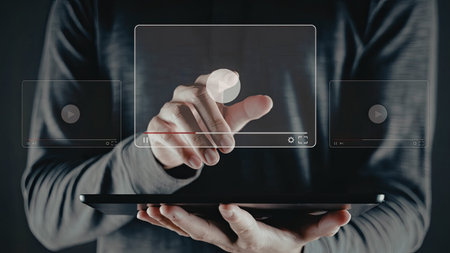 A person is holding a tablet and interacting with a digital interface using their finger. The image...