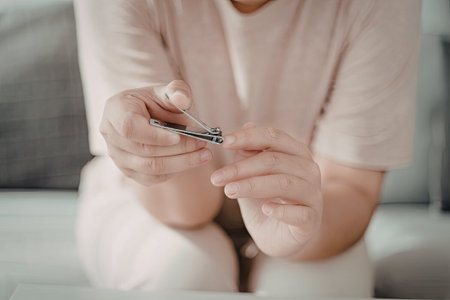 A close-up image of a person trimming their fingernails with nail clippers.の写真素材