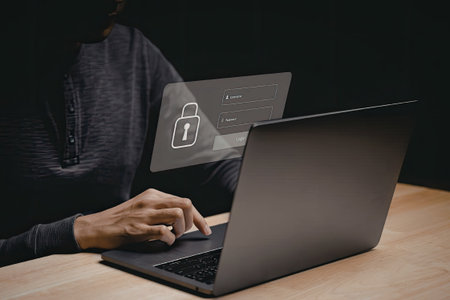 A person is typing on a laptop which displays a security lock screen with a padlock icon. The scene conveys themes of cybersecurity and online protection.の写真素材