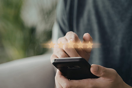 A close-up image of a person holding a smartphone and giving a star rating, likely indicating a...