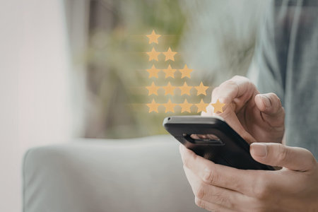 A person is holding a smartphone, giving a star rating with their hand. The image emphasizes the...